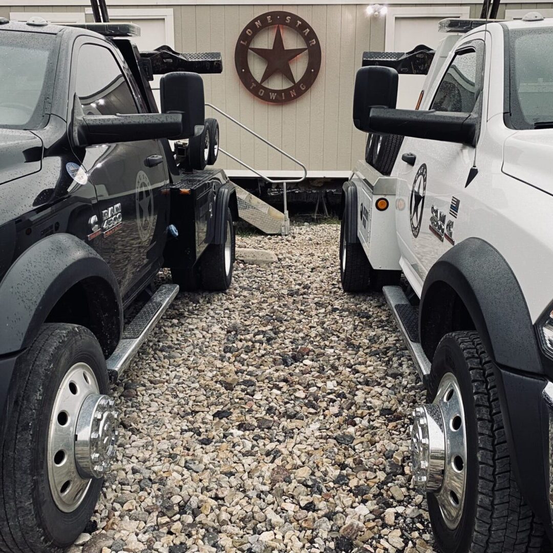 Two trucks parked in a gravel lot with a texas star on the back of them.